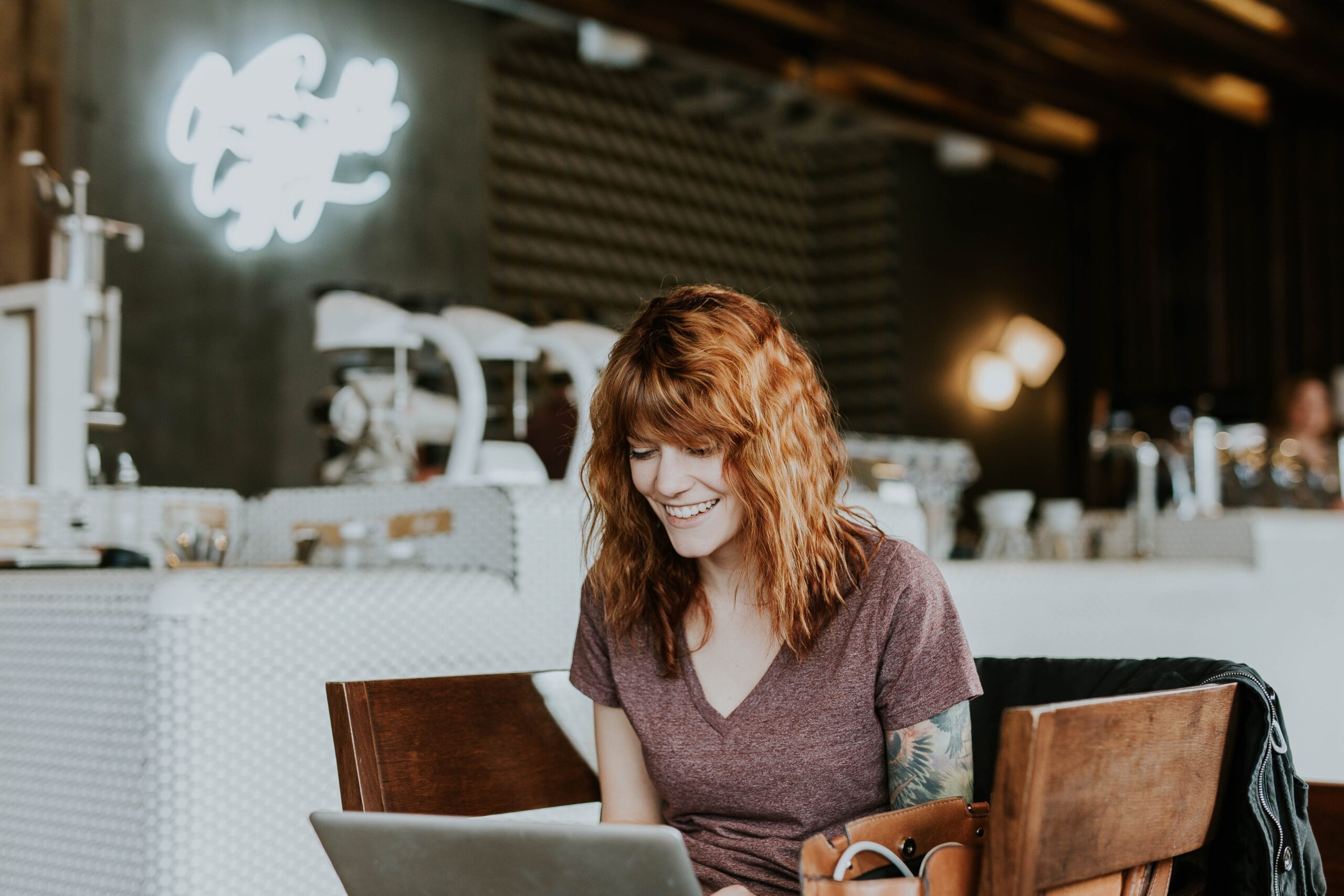 Smiling girl sitting in a cafe with her laptop